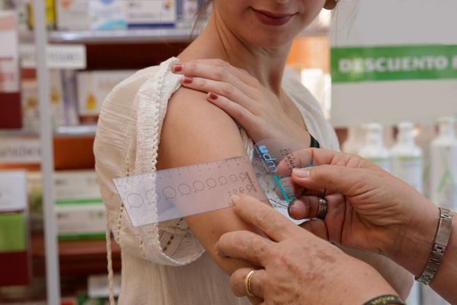 Usuària participant en la campanya sent avaluada a la farmàcia amb l’ajuda d’una regleta dermatològica